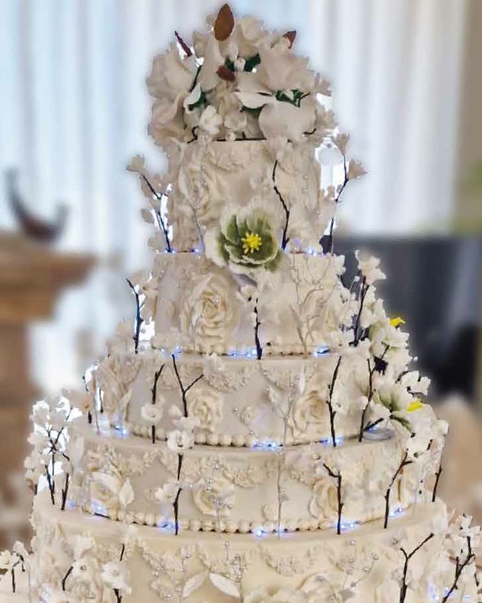 Tarta de boda blanca de siete pisos con flores y luces en Marbella